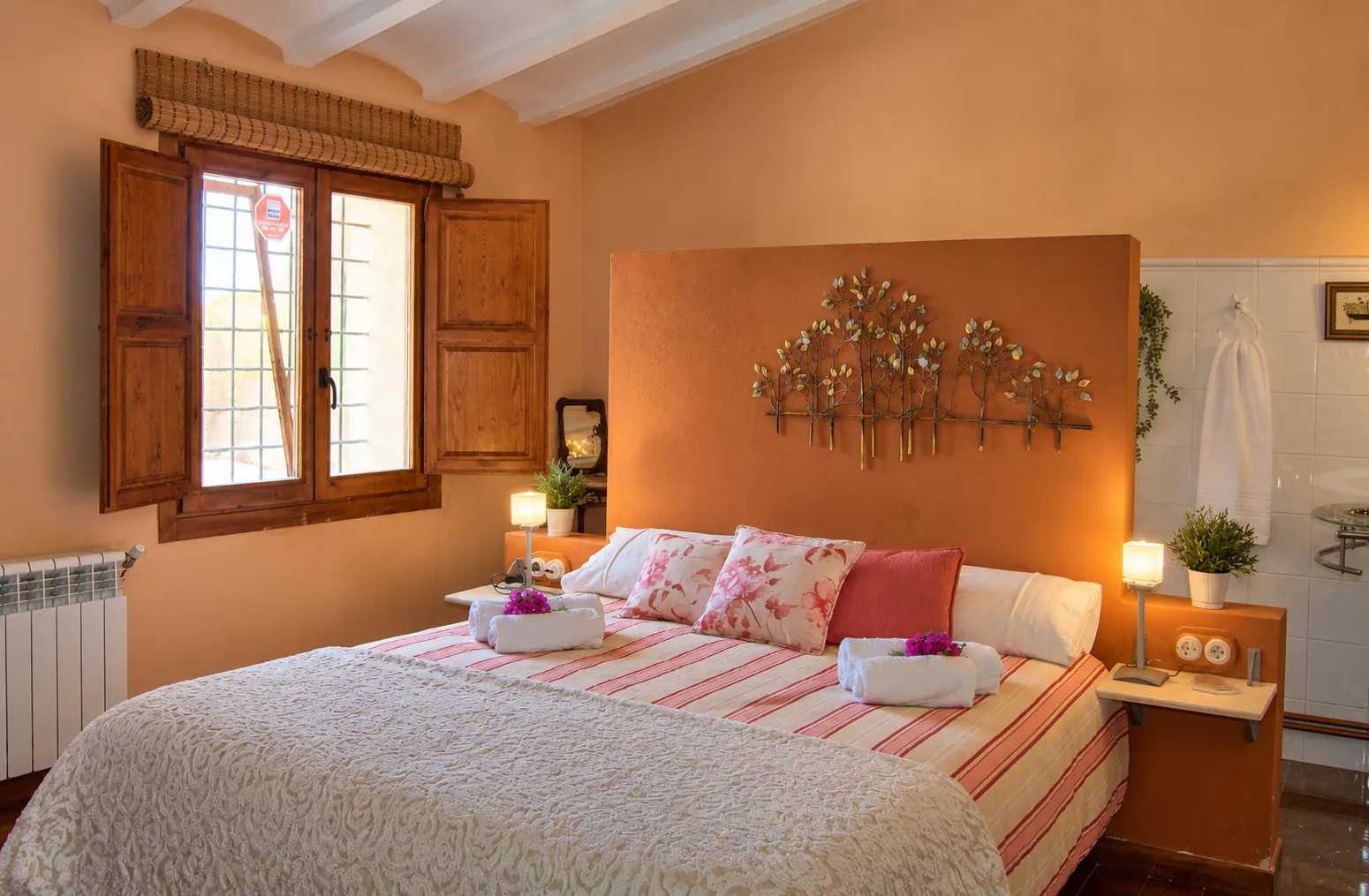 Habitación doble con cabecero terracota y ventana de madera