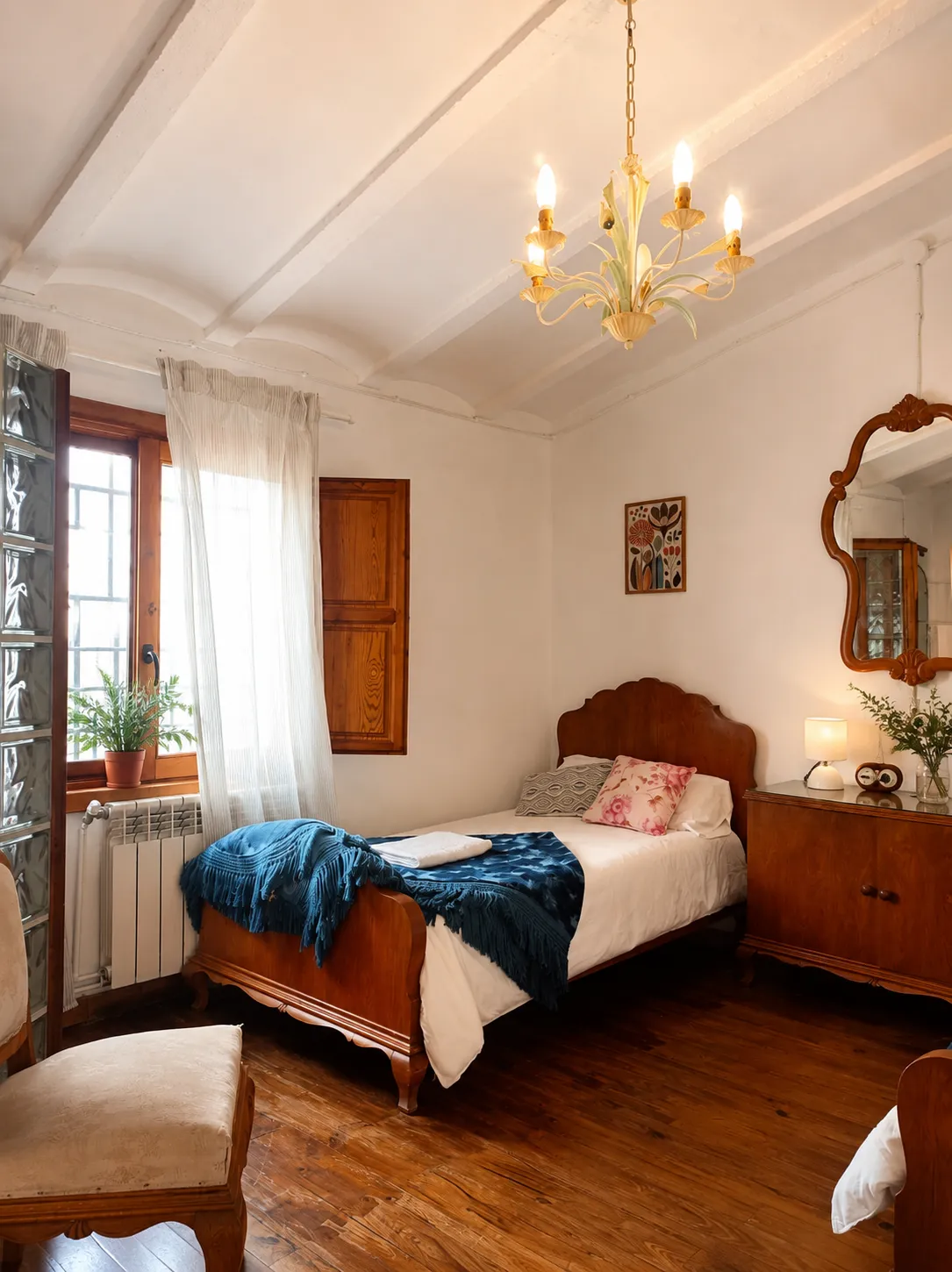 Habitación con cama de madera, manta azul y ventana con contraventanas
