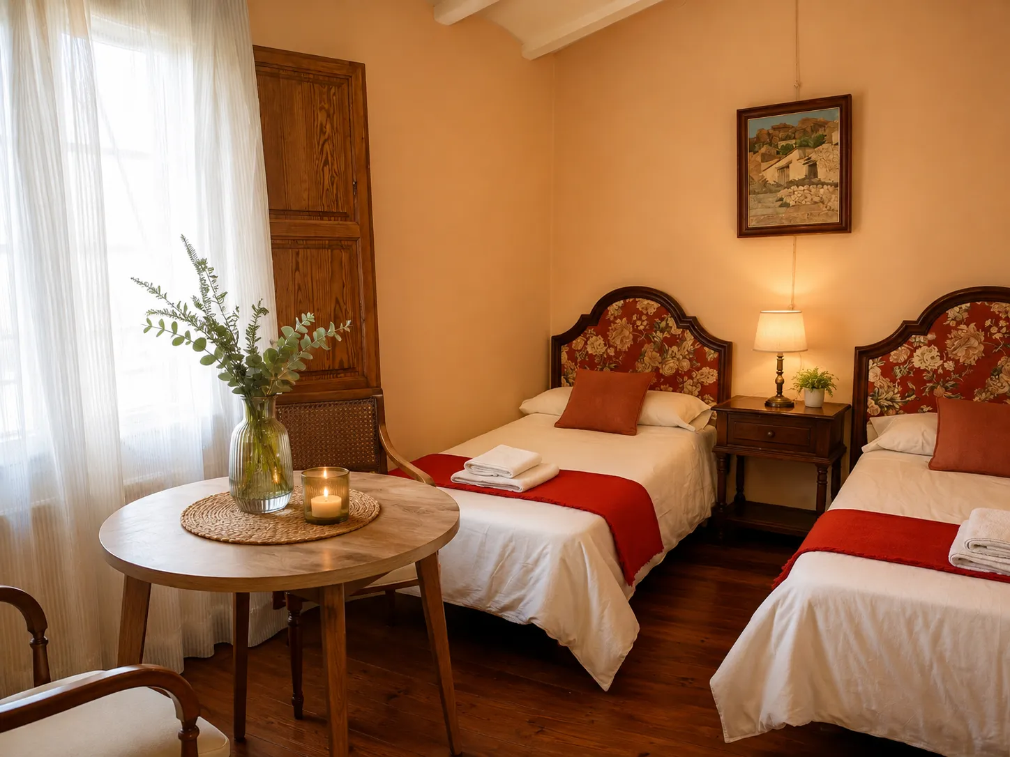 Habitación con dos camas individuales, cabeceros florales y mantas rojas