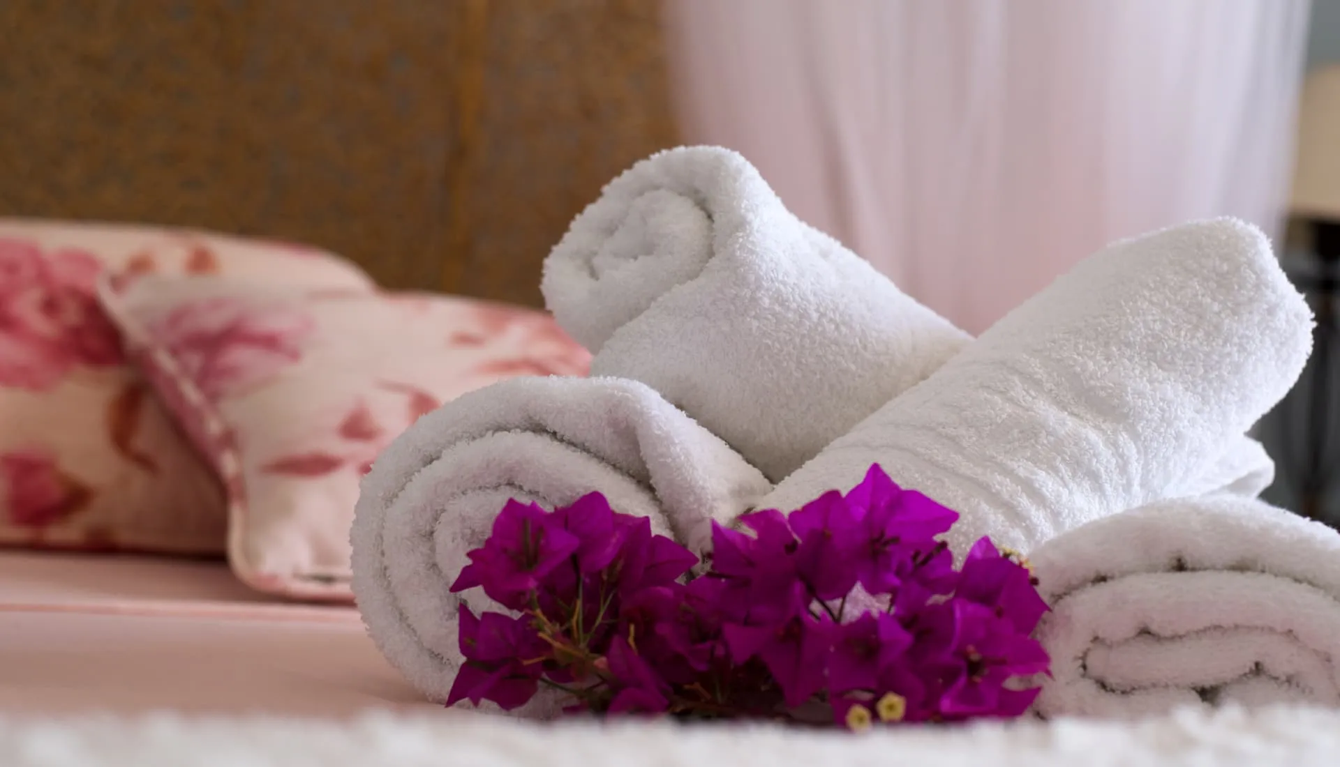 Detalle de toallas dobladas con buganvilla sobre la cama