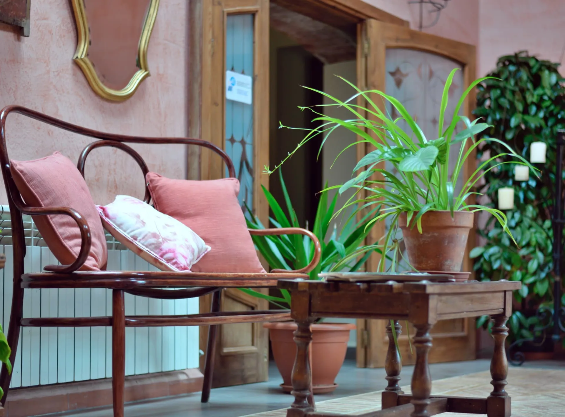 Rincón de la masía con sillón de madera, cojines y plantas