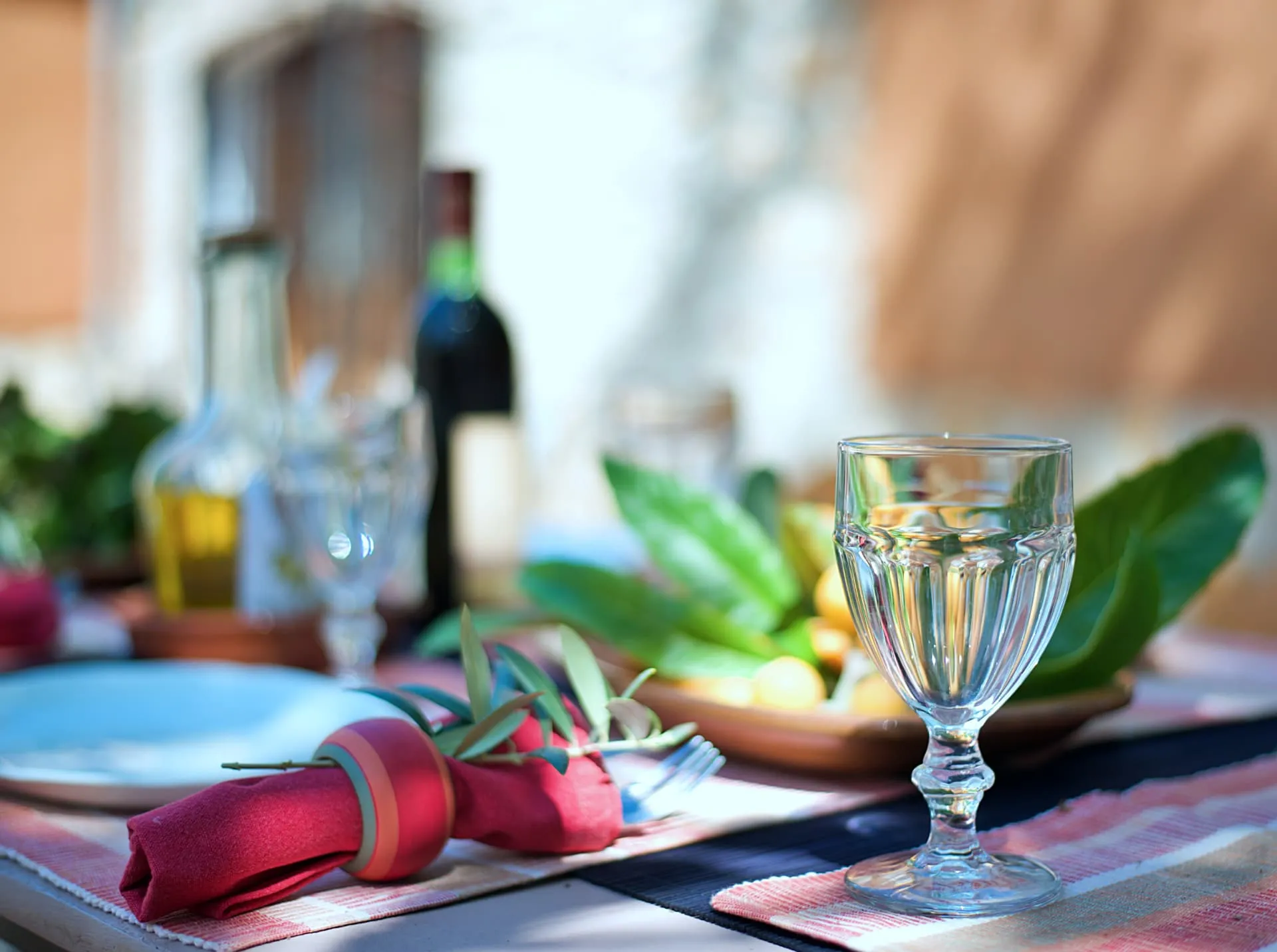 Mesa preparada con copa, servilleta roja, aceite y verduras
